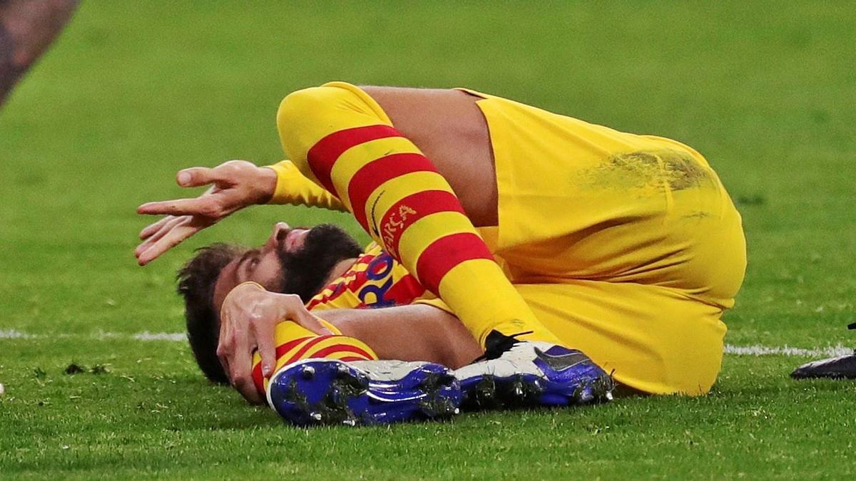 Piqué, tras caer lesionado, se toca la rodilla y reclama la ayuda médica. |  // JUANJO MARTÍN