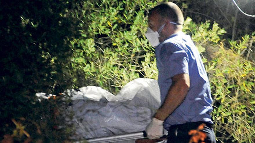 Operarios de la funeraria sacan el cadáver de la zona boscosa próxima a Lloret en la que fue hallado.