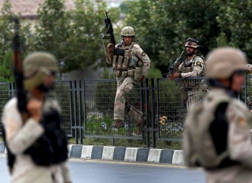 Members of Afghan security forces climb over a fence as they arrive at the site of an attack near the Afghan parliament in Kabul, Afghanistan