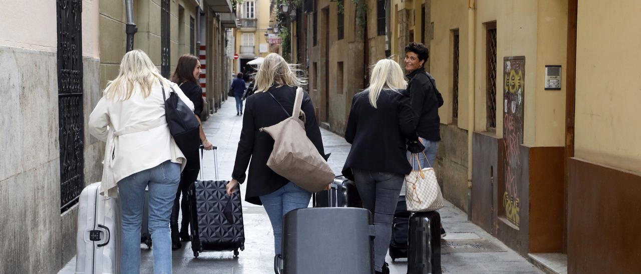 Un grupo de turistas con maletas en busca de su apartamento en el centro.