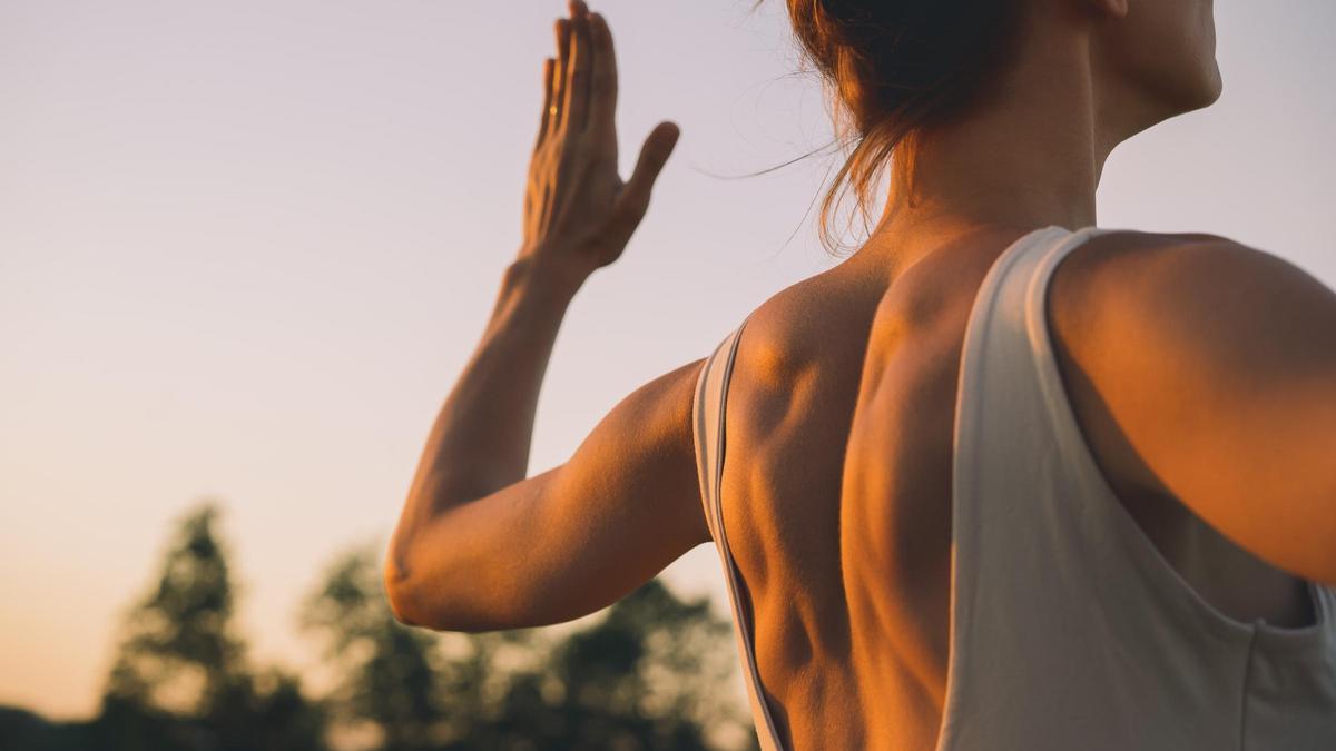 Mujercon colchoneta de yoga se prepara para practicar yoga al aire libre