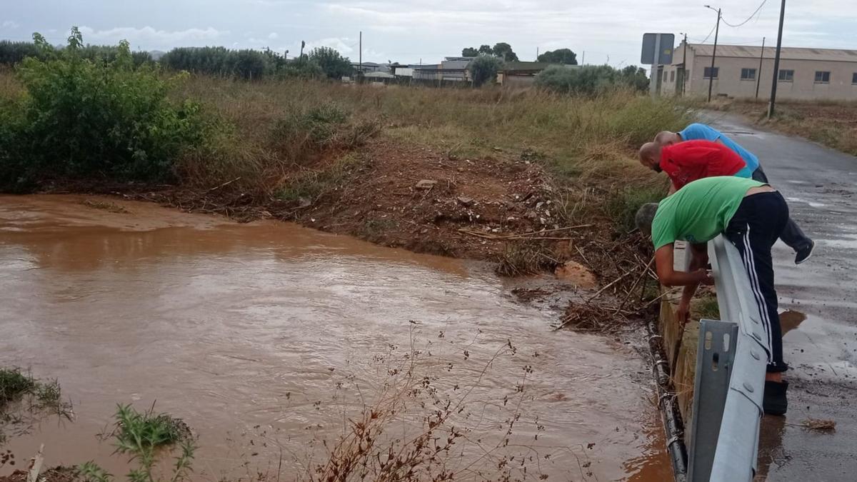 Vecinos de La Palma (Cartagena) tratan de limpiar el paso de unarambla bajo una carretera.