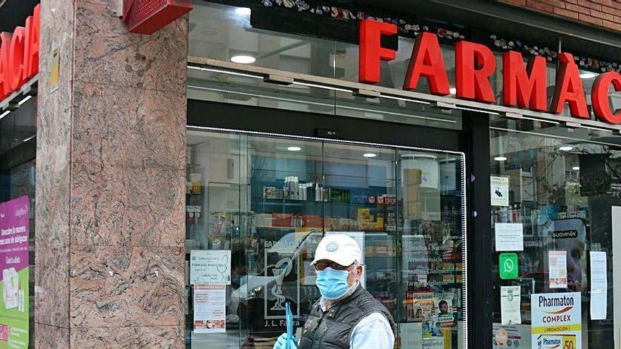 Un home espera al carrer amb les receptes mèdiques a la mà.