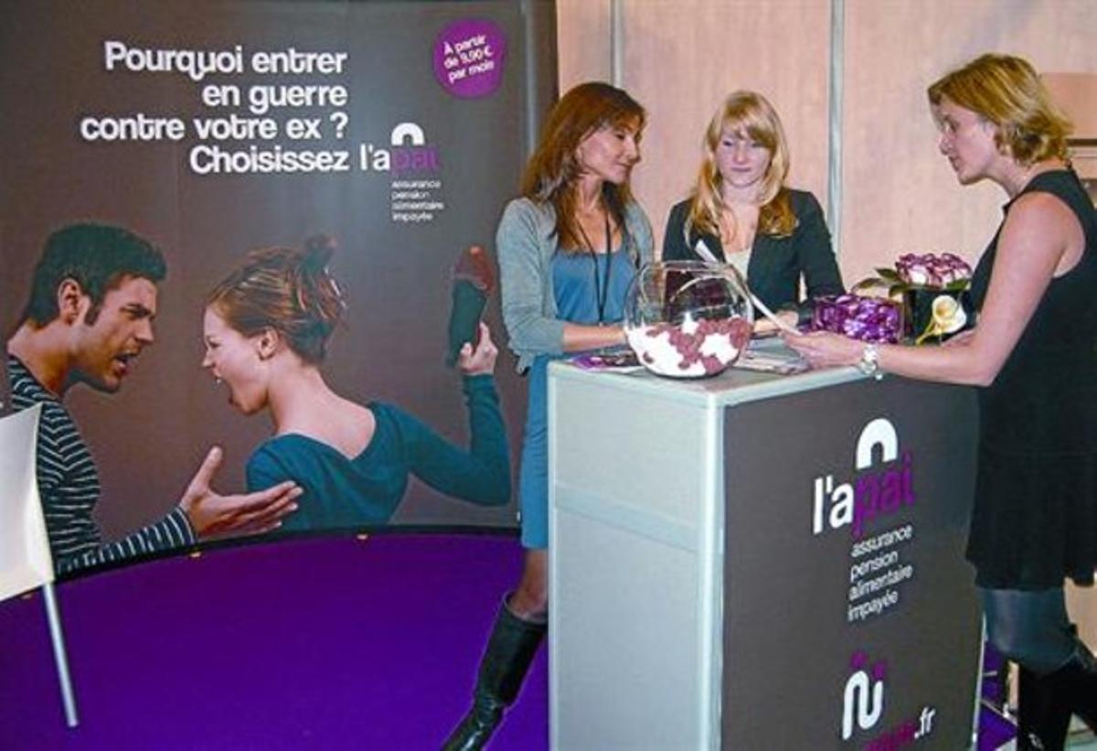 Tres mujeres, en un estand de una firma de seguros para pensiones alimentarias.