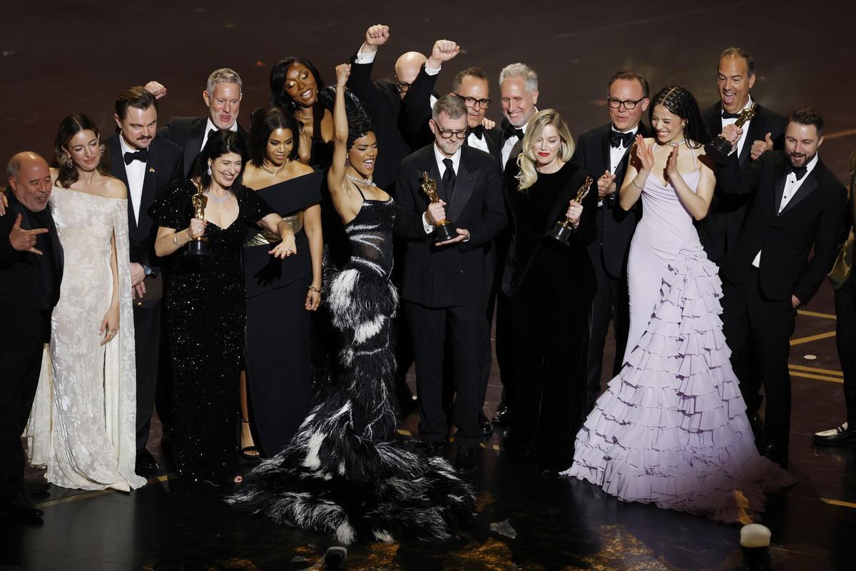 Paul Thomas Anderson (C) y la productora Sara Murphy (centro derecha) celebran con el elenco y el equipo en el escenario tras ganar el Oscar a la Mejor Película por 'Una batallas tras otra'.