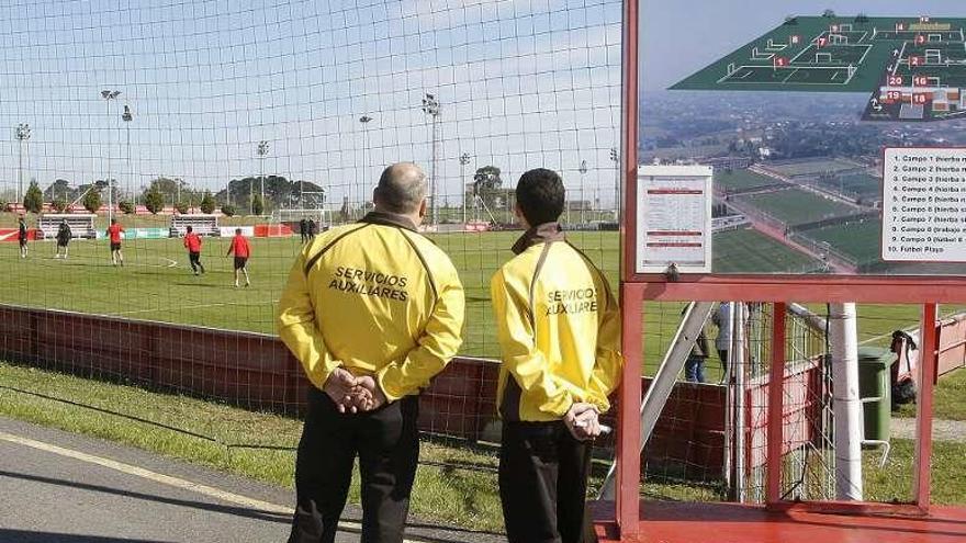 Dos empleados de seguridad siguen el entrenamiento rojiblanco de ayer.