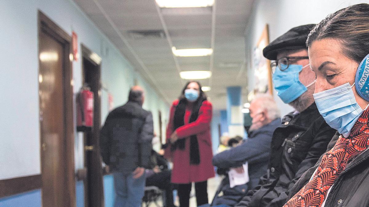 Pacientes de un centro de salud esperan a ser atendidos, con la mascarilla.