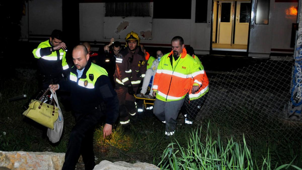 Bomberos y personal del SEM trasladan a una pasajera lesionada, ayer, por el descarrilamiento de un tren cerca de Sitges.