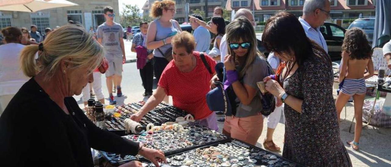 Una &quot;collareira&quot; ofrece sus artesanías a turistas en la isla de A Toxa. // Muñiz