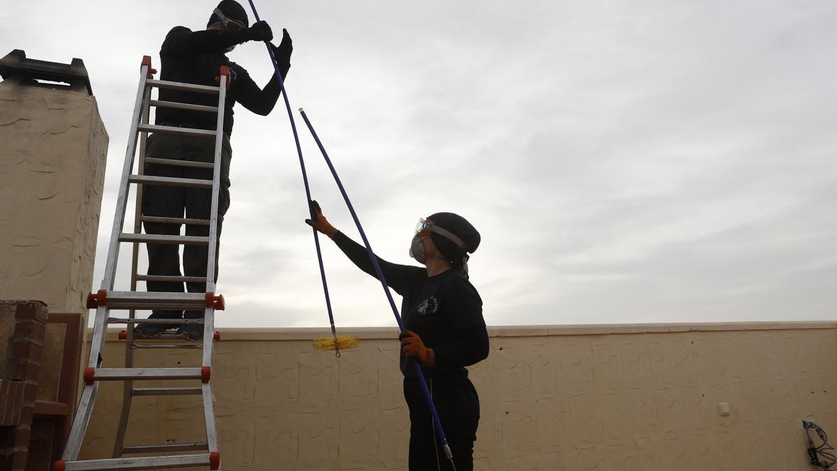 Los deshollinadores, equipados con mascarillas, utilizan distintas herramientas para limpiar a fondo las chimeneas