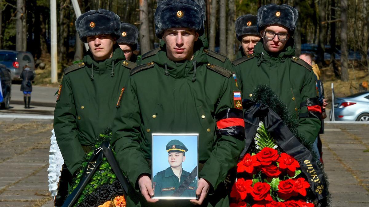 Soldados rusos llevan coronas y una foto del militar ruso Nikita Avrov, de 20 años, durante su funeral en Luga, a unos 150 km al sur de San Petersburgo, el 11 de abril de 2022, después de su muerte el 27 de marzo, durante la actual invasión rusa de Ucrania.