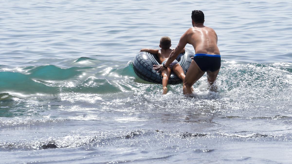Un padre juega con su hijo en Playa del Águila.