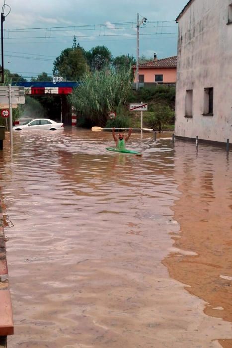 Un veí de Bordils va en kayak per un dels carrers on ha quedat un vehicle atrapat per la pluja