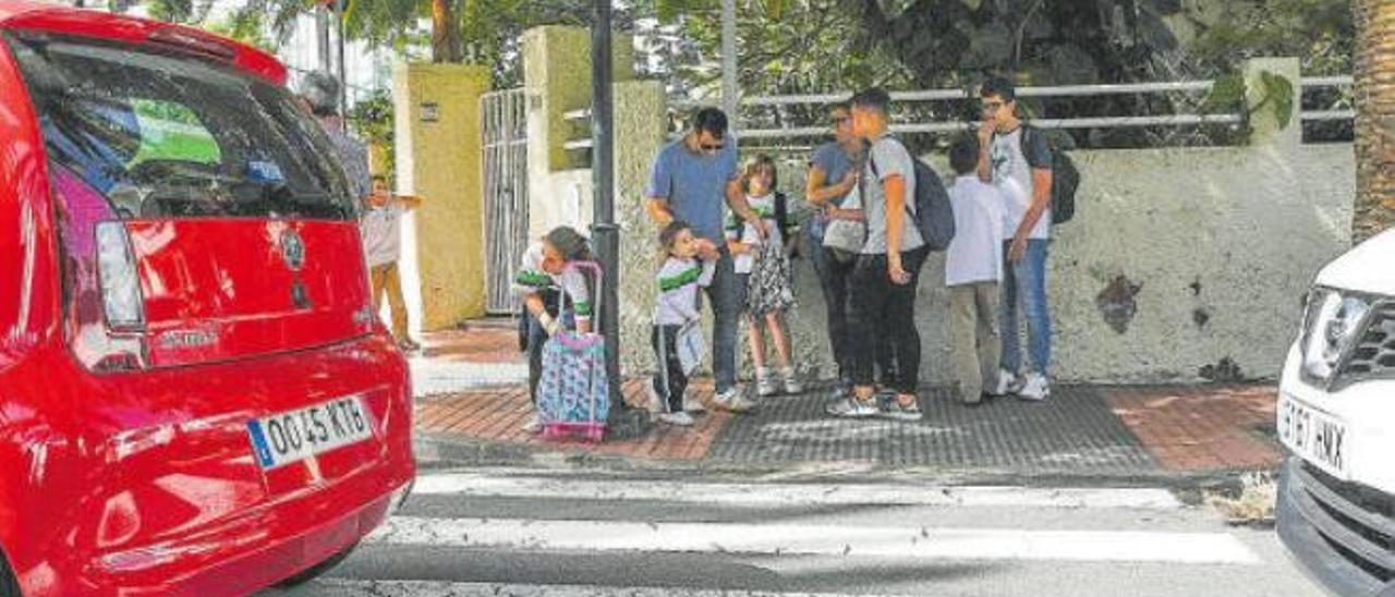 Escolares a la hora de salida del colegio en Ciudad Jardín frente a un paso de peatones.