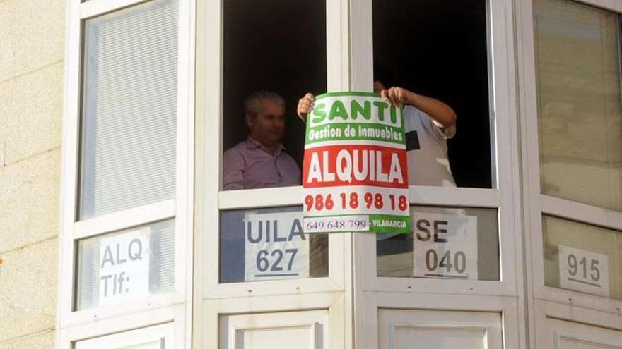 El dueño de una vivienda en la playa de A Concha cuelga un cartel para alquilarla en verano.