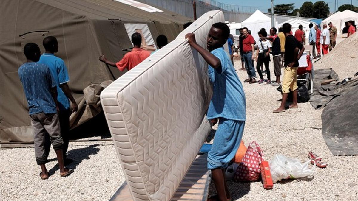 Un eritreo carga con un colchón en un campo de refugiados en Roma.