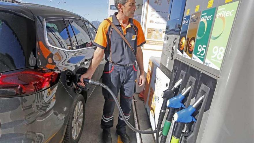 Un empleado de una gasolinera surte combustible a un vehículo.