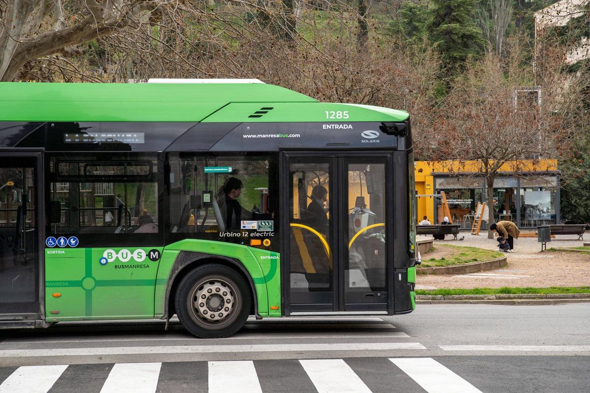 Un bus urbà a la plaça Espanya, aquesta tarda, i, al fons, el Bar Plaça, on s'insta els conductors a anar al vàter