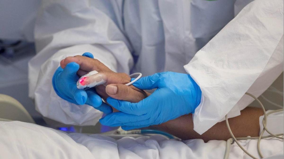 Una enfermera sujeta la mano de una paciente en el hospital.