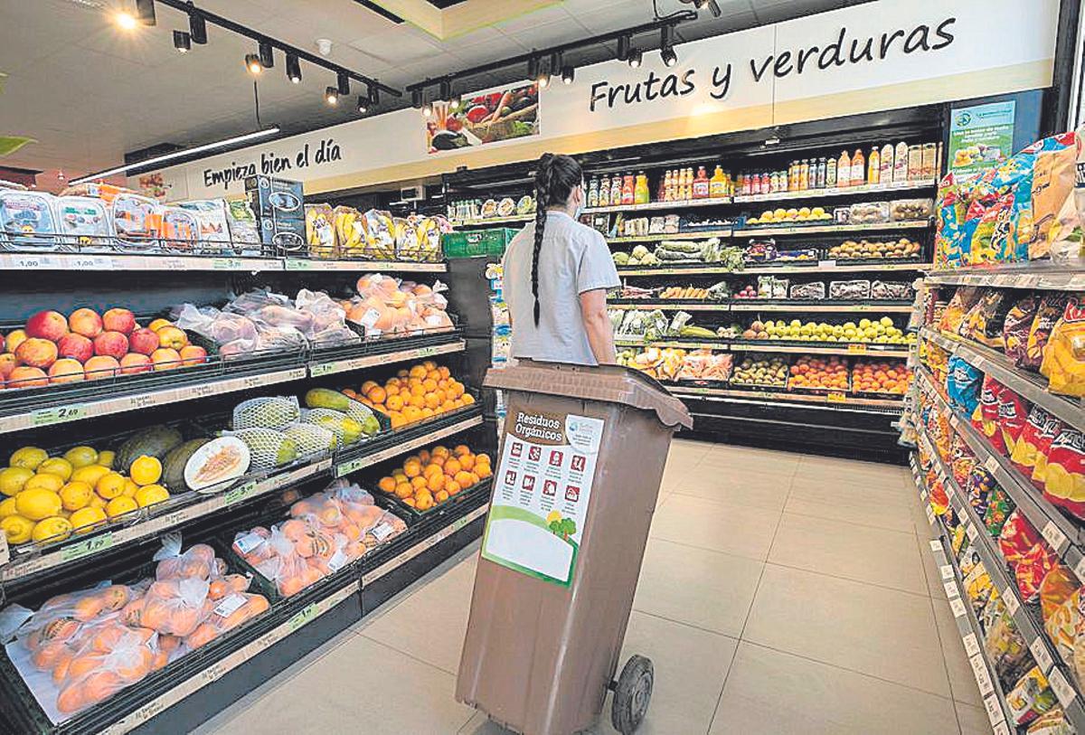 Una dependienta carga un cubo de basura en un supermercado del Archipiélago.