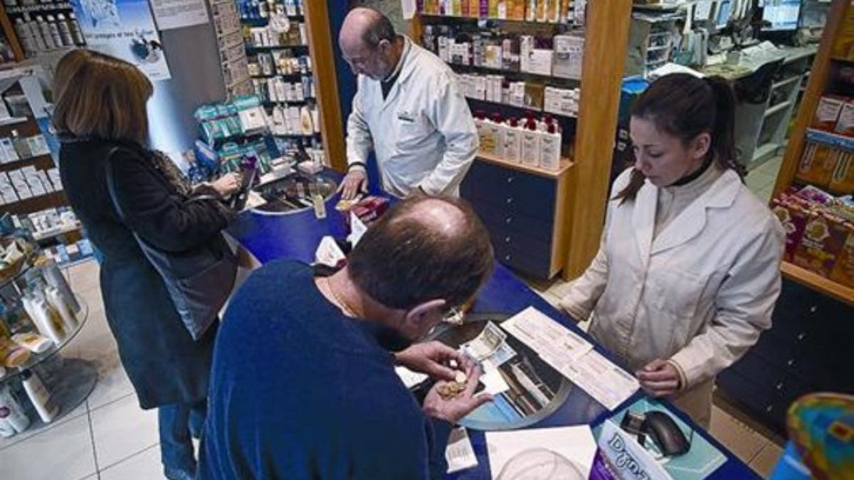 Dos farmacéuticos atienden a sendos clientes en un comercio de Barcelona.