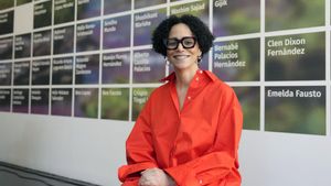 La artista cubano-estadounidense Coco Fusco con una de sus obras detrás, compuesta por los nombres de periodistas, artistas y activistas medioambientales en prisión o asesinados en 2023. 