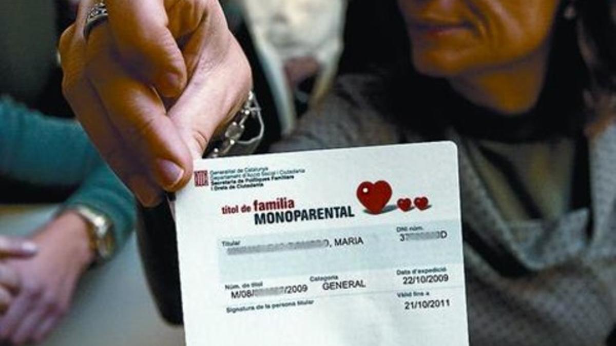 Una mujer muestra su carnet de familia monoparental.