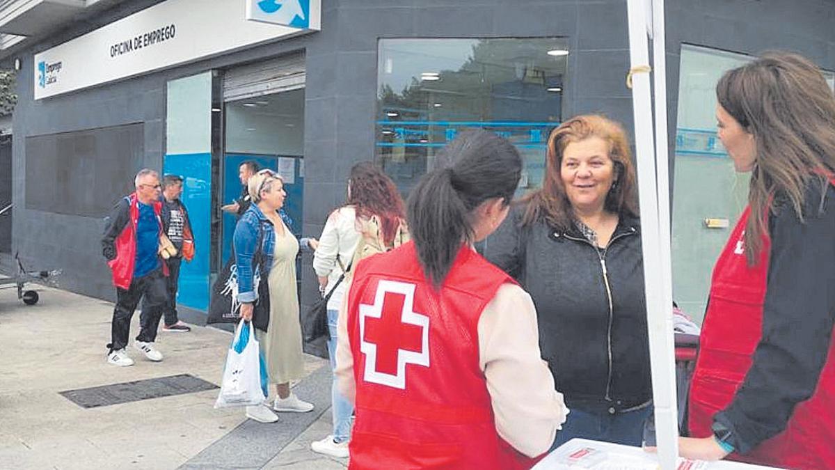 Dos chicas informan sobre el plan de Cruz Roja frente a una oficina de empleo