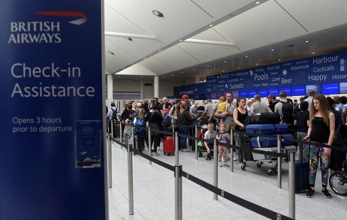 People queue with their luggage for the  British ...