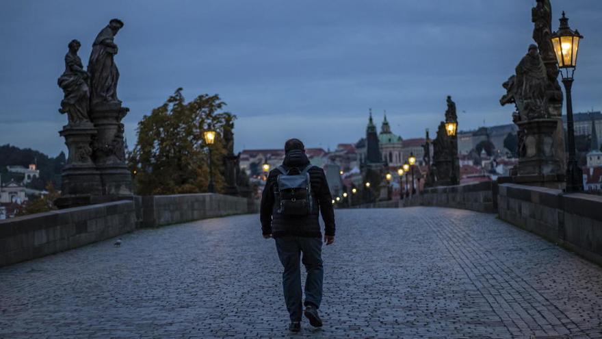 Un hombre camina por el Puente de Carlos, en Praga, casi desierto