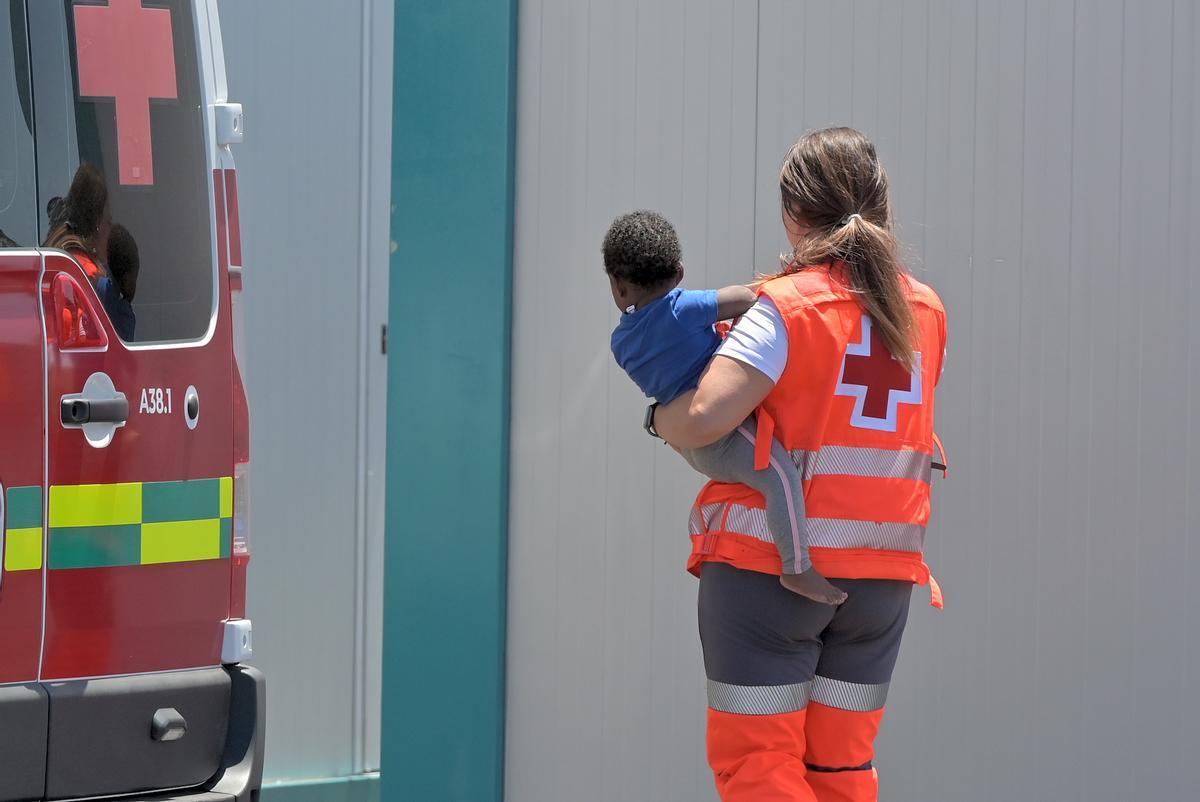 Imagen de una trabajadora de los servicios de Cruz Roja junto a un niÃ±o que llego a El Hierro a bordo de un cayuco junto a 63 inmigrantes en junio de 2024. EFE/Gelmert Finol