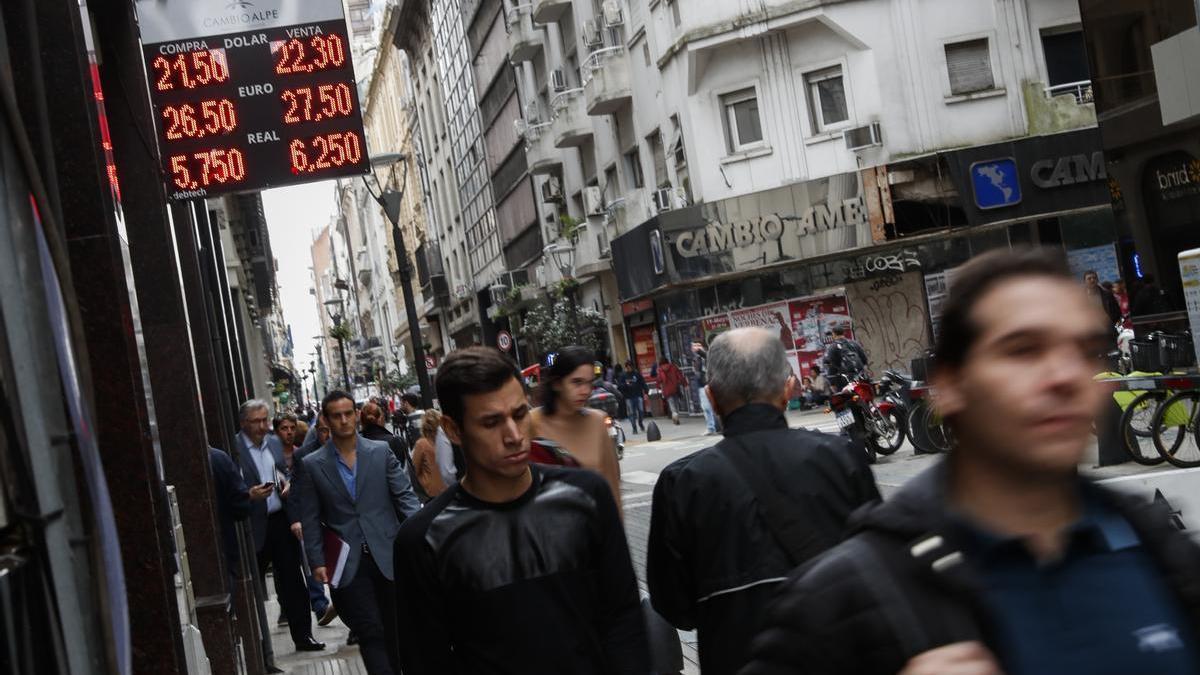 Varios transeúntes pasean por delante de una oficina de cambio de moneda en Buenos Aires.