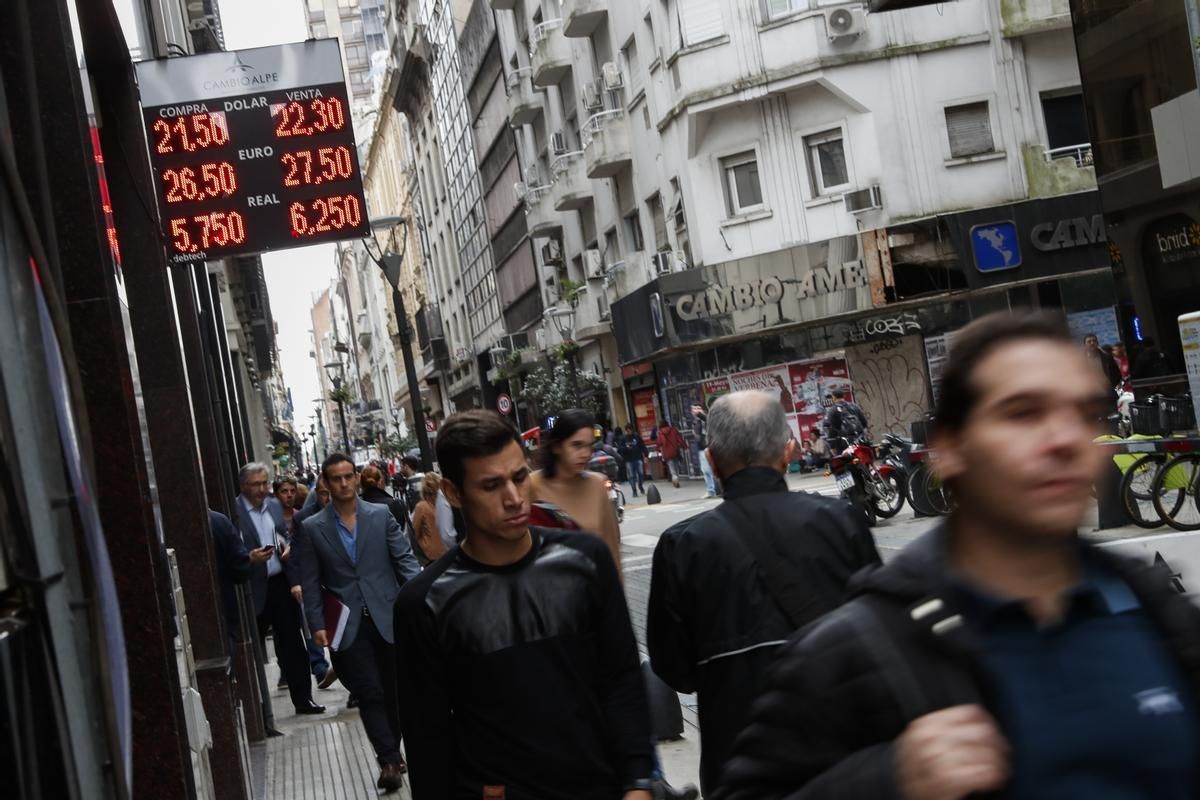 Varios transeúntes pasean por delante de una oficina de cambio de moneda en Buenos Aires.