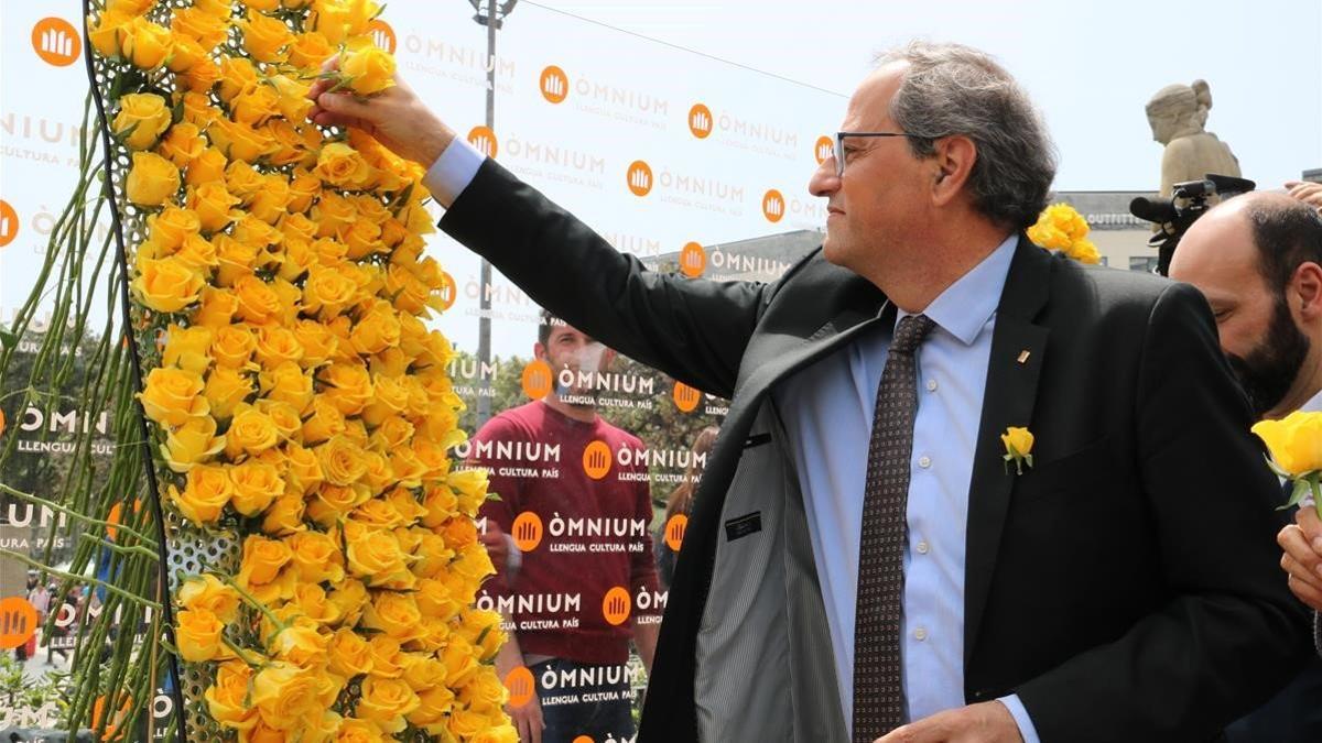 El presidente Quim Torra coloca una rosa amarilla en el mural de Òmnium.