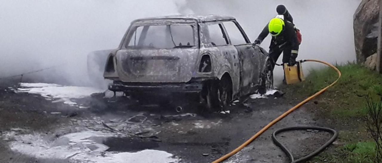 Un trabajador de Emerxencias de Vilagarcía, junto al coche calcinado.  |  // CEDIDA