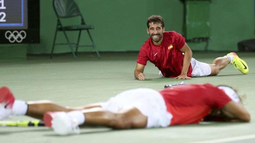 Marc López busca con la mirada a Nadal, con ambos tumbados en el suelo tras el último punto. // Levin Lamarque