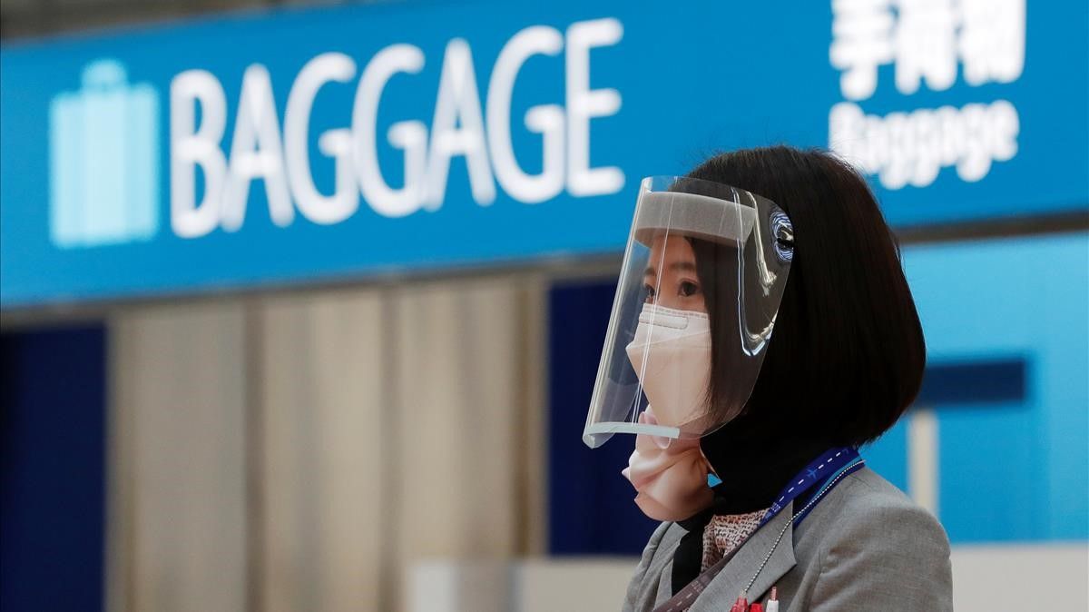 A staff of All Nippon Airways (ANA) wearing a visor stands in front of a gate at an almost empty departure terminal of Haneda Airport  where fewer people than usual are seen during Golden Week holidays following the coronavirus disease (COVID-19) outbreak  in Tokyo  Japan April 29  2020  REUTERS Kim Kyung-Hoon