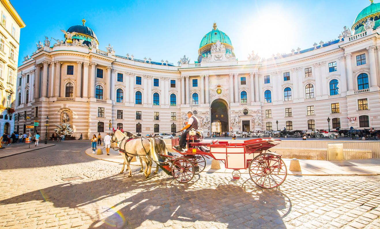 Palacio de Hofburg y coche de caballos en la soleada calle Viena, Austria