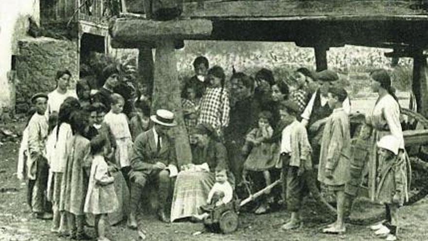 Aurelio del Llano, tomando notas rodeado de vecinos en un pueblo de Asturias. | LNE
