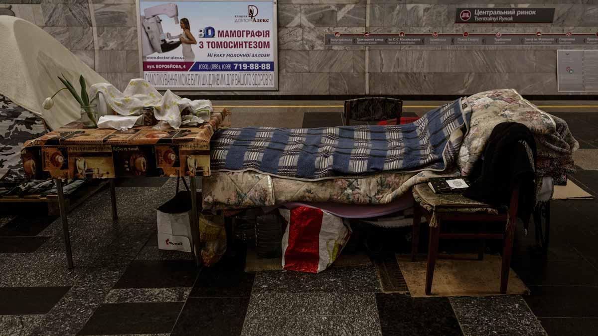 Una de las improvisadas camas que ya llevan seis semanas albergando a ciudadanos en el metro de Járkov. Una silla con un libro y una mesa con una flor acaban de componer el espacio donde se resguarda esta persona.