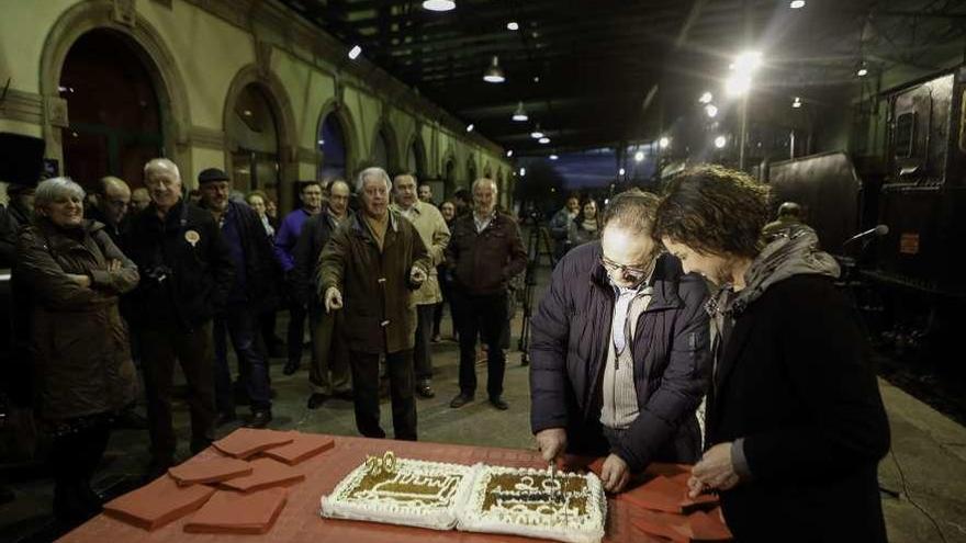 Javier Fernández, acompañado de la concejala Montserrat López, corta la tarta de aniversario en el andén del Museo del Ferrocarril de Asturias.