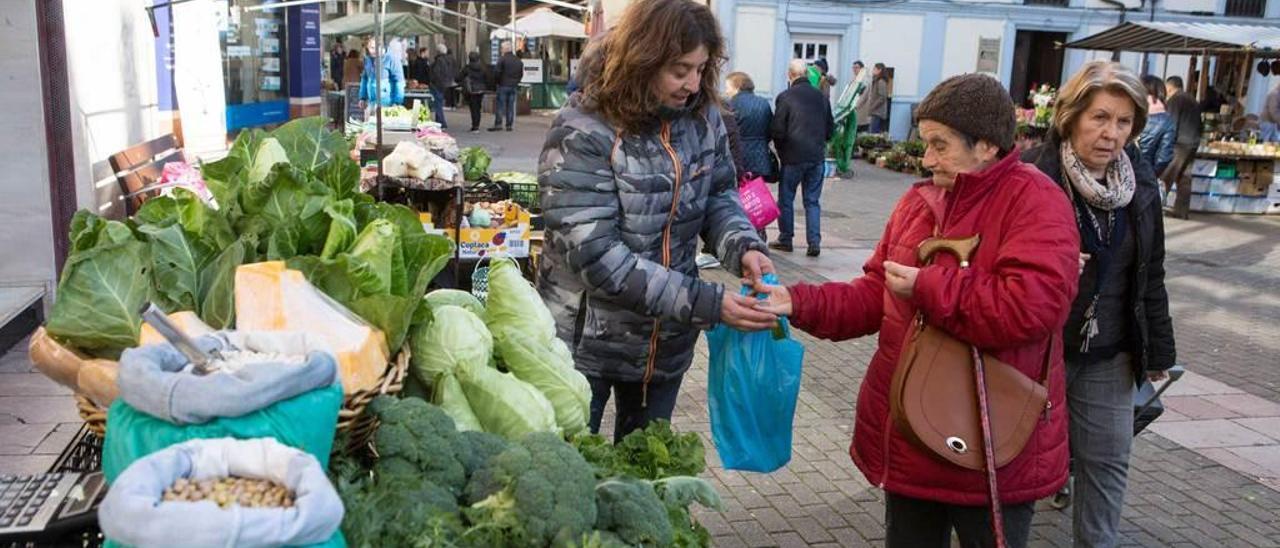 Marta Bobes vendiendo a Carmen García hortalizas, ayer, en su puesto en el mercado semanal de Grado.