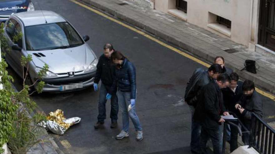 Varios policías en el lugar del crimen, donde al fondo se ve el bolso de la víctima.