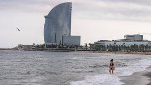 Una joven se adentra en el mar, en la playa de la Barceloneta de Barcelona.