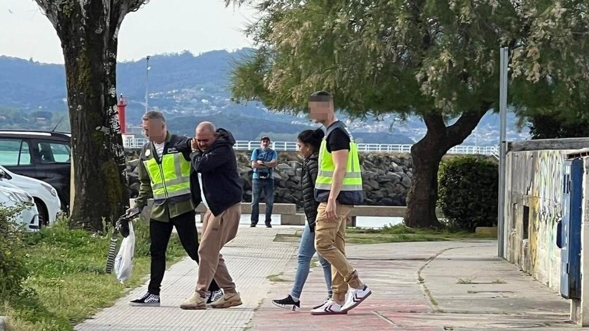Dos policías conducen a los detenidos desde la alameda nueva de Cangas a los coches.