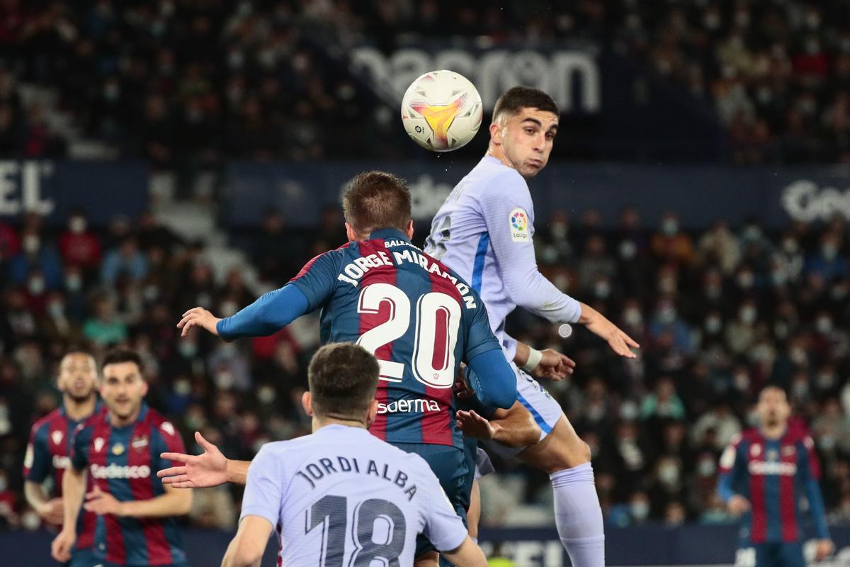 El delantero del FC Barcelona Ferrán Torres (d) cabecea un balón ante Jorge Miramón (c), del Levante. 