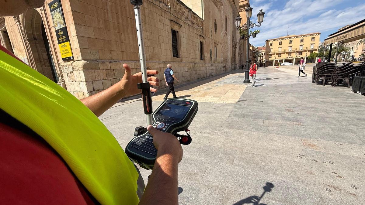 Un topógrafo hace las mediciones en la plaza frente a la basílica de Elche
