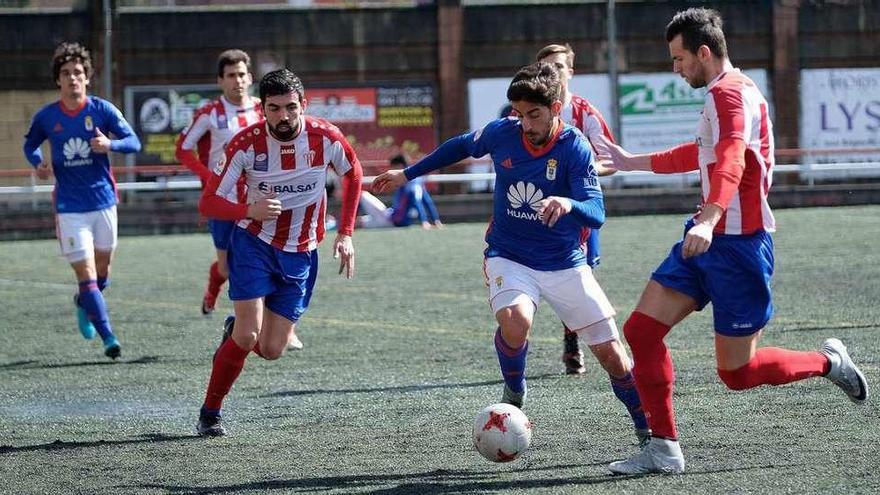 Ernesto, con el balón, entre dos jugadores de L&#039;Entregu.