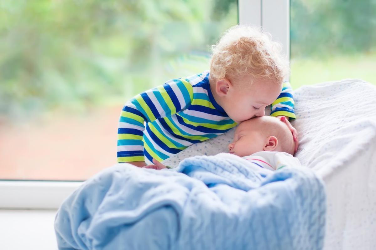 Niño pequeño besando a su hermano recién nacido.