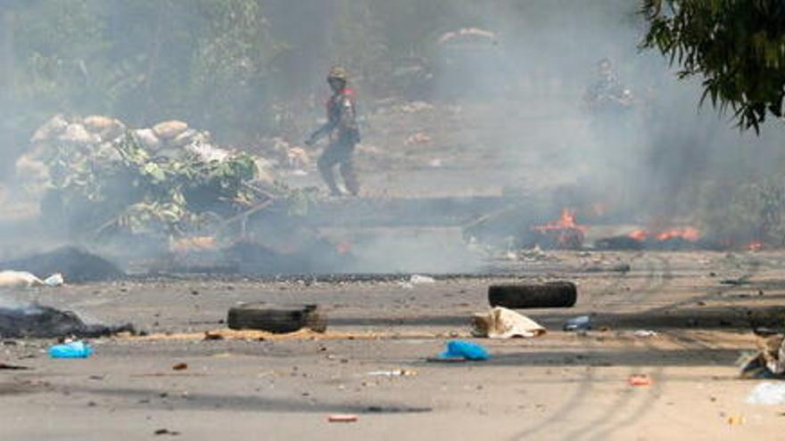 Un carrer de Yangon, amb destrosses i focs, durant les protestes contra el cop d&#039;estat, el 27 de març del 2021